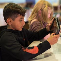 school age boy holding ipad